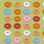 Barevné donuty s polevou a posypem uspořádané v mřížce na zeleném pozadí
