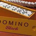 Dřevěná krabička s dominovými kameny na červeném povrchu, s nápisem DOMINO Block na víku