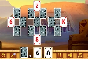 Karty uspořádané do tvaru kříže na pozadí egyptské pouště s pyramidami a sochami