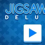 Modrá obrazovka s nápisem Jigsaw Deluxe a bílým tlačítkem s modrou šipkou uprostřed ve tvaru puzzle