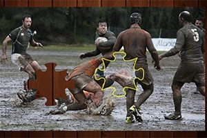 Mužský tým hraje rugby v blátivém terénu s chybějícím dílem skládačky uprostřed