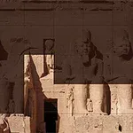 Kamenné sochy faraonů vytesané do skalního útesu s postavami sedících velikánů a hieroglyfy