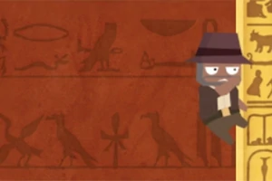 Postavička v klobouku leze po zdi s hieroglyfy na pozadí