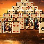 Hromada hracích karet uspořádaná do pyramidového tvaru na egyptském pozadí při západu slunce